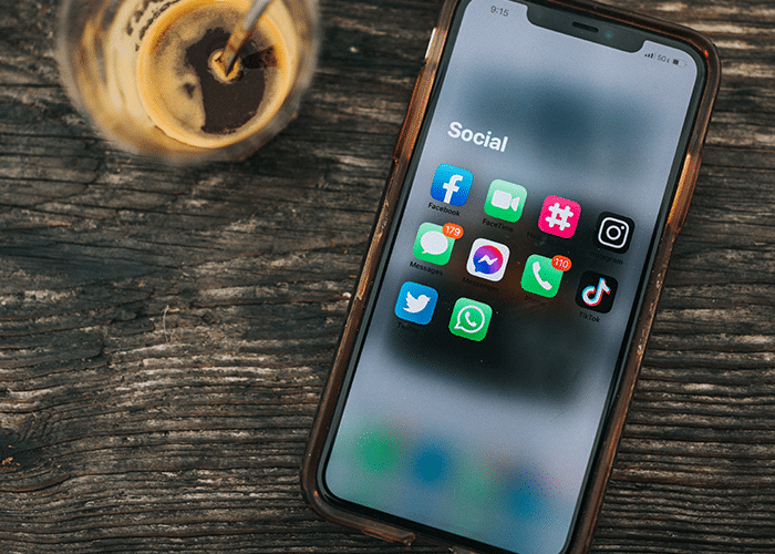 iphone with social media icons next to cold brew coffee