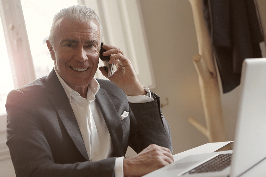 male commercial real estate agent sitting in office talking on phone while on computer