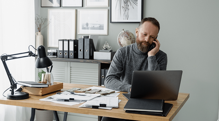 middle aged white man with beard compiling broker opinion of value for commercial real estate customer in office