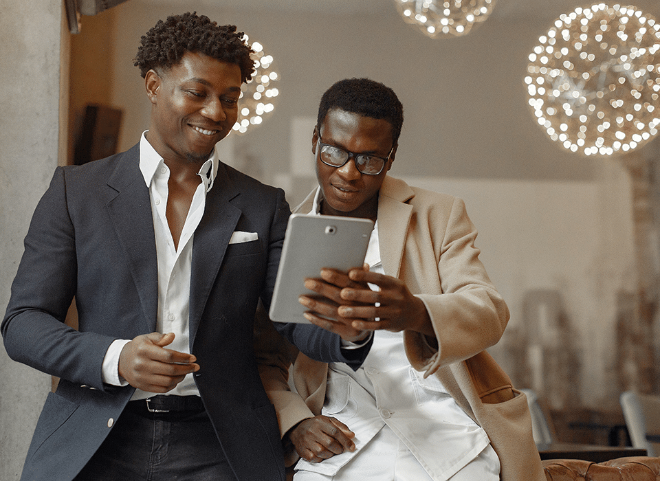 two professional black millennial men looking at real estate statistics on a tablet