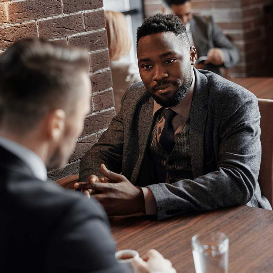 african american male with beard and suit talking with another person in restaurant