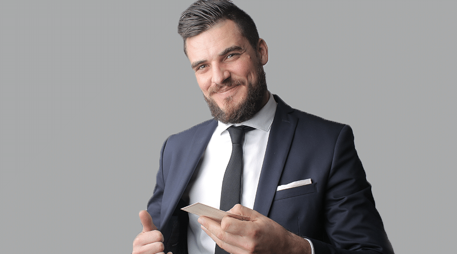 caucasian millennial man with beard handing business card out of suit jacket pocket