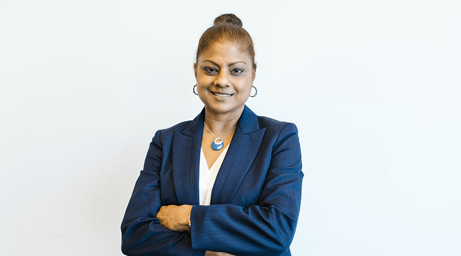 indian female experienced real estate agent wearing blue suit with arms crossed smiling