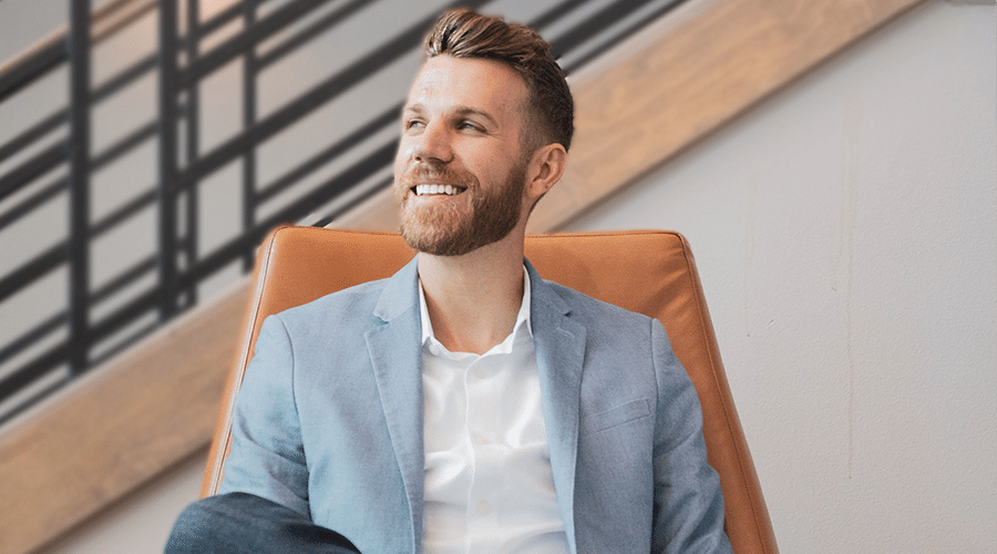 millennial real estate agent male with blue blazer smiling in leather chair