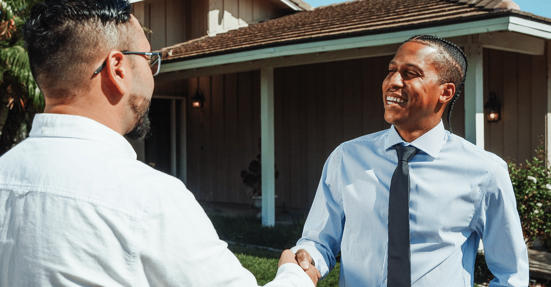 successful male real estate agent in tie smiling shaking hands with customer