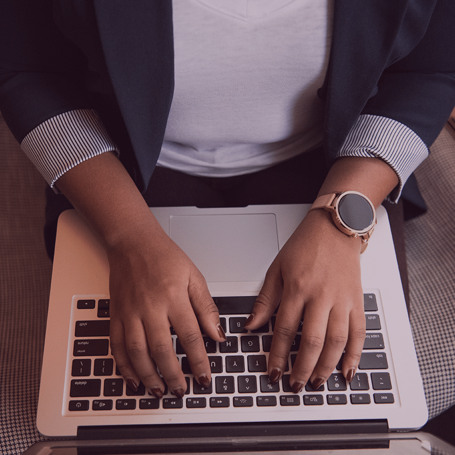 woman hands typing on laptop keyboard wearing gold and black smart watch