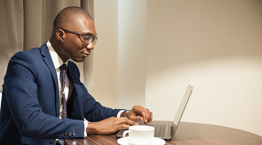 young african american male wearing glasses and suit new to real estate looking at laptop