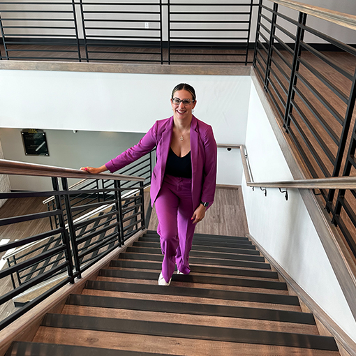 casey bryan, president, walking up stairs in magenta pant suit